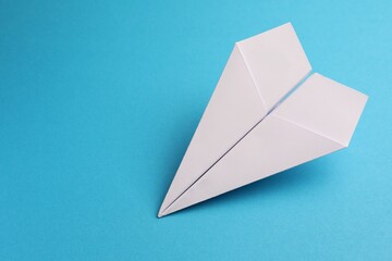 Handmade white paper plane on light blue background, space for text