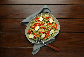 Delicious salad with Chinese cabbage and quail eggs served on wooden table, top view