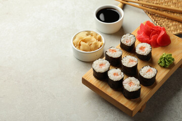 Tasty sushi rolls served on grey table. Space for text
