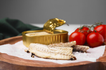Delicious canned mackerel fillets and fresh tomatoes on wooden plate, closeup