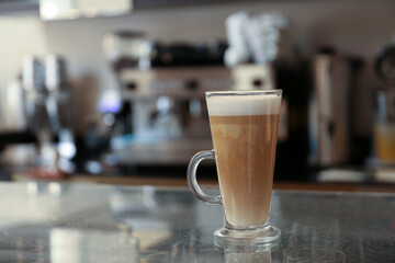 Glass with delicious coffee on countertop in cafe indoors, space for text