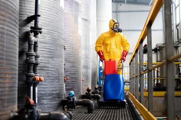 Professional worker in protection suit and gas mask transporting aggressive chemicals inside...