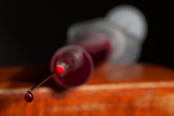 the vaccination syringe is filled with blood, there is a drop on the needle.