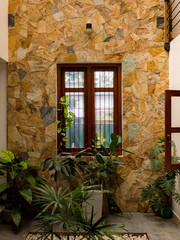 Fototapeta na wymiar indoor courtyard of house with window and plants, skylight above, stone wall made from unpolished granite