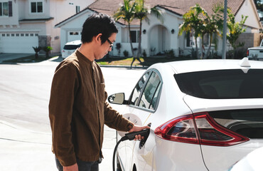 A man is charging his electric car at home. Alternative energy because the high-rise gas price is increasing.
