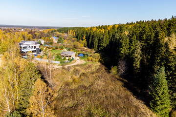 Panoramic view of country housing surrounded by coniferous forest, autumn landscape