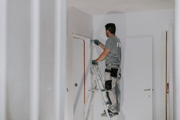 A young builder is plastering a doorway.