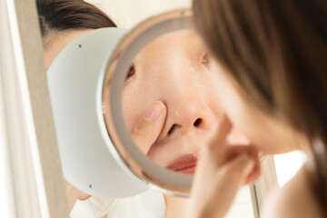 Obraz na płótnie Canvas 鏡で鼻を見る女性