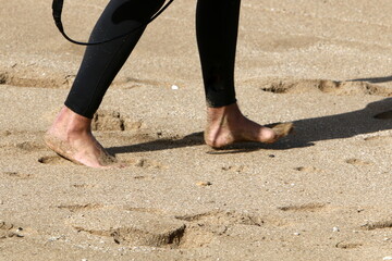 A man walks barefoot on the sand by the sea