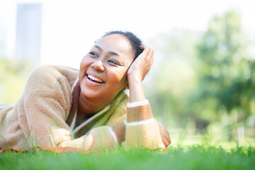Dreaming portrait concept. African American woman smiling with perfect smile and white teeth in a park and looking at natural at park.