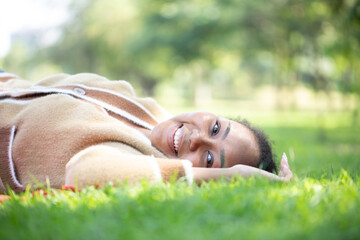 The cute woman lay on the grass against the background of the sunshine