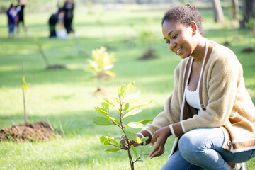 Charming woman with tree seedling as climate change tree for sustainable reforestation in the park...