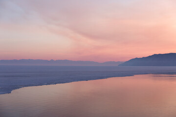 Beautiful sunset on frozen lake Baikal. Winter landscape.