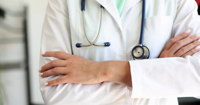 Doctor physician or cardiologist in a white medical coat stands with crossed arms with a stethoscop