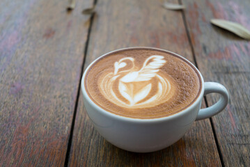 Latte art coffee with swan shape in coffee cup on wooden background, Hot drink