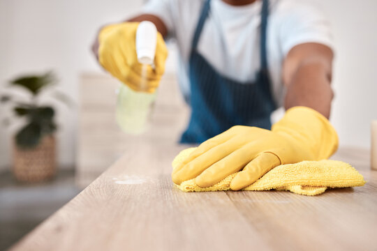 Black man, hands and spray bottle and cleaning cloth on house table, home desk or office building counter top. Zoom, gloves and fabric bacteria product for hygiene maintenance and healthcare wellness