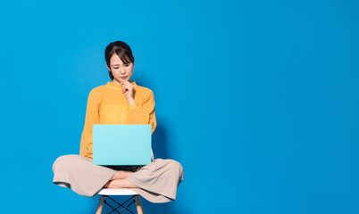 ノートパソコンを見ながら考える女性