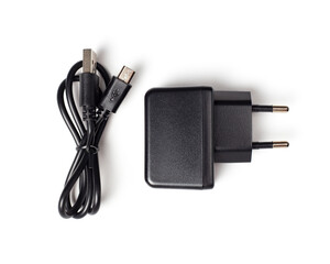 Black charger on a white background, top view. Charger adapter and micro usb cable.