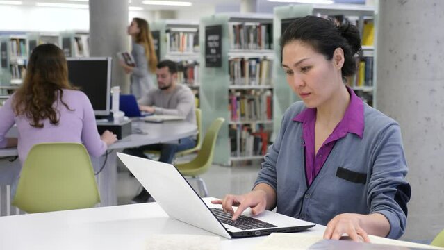 Woman engaged in self-education using pc for searching information in public libraryary