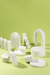 An empty stage with a composition of white podiums of different sizes and shapes on a green background and shadows
