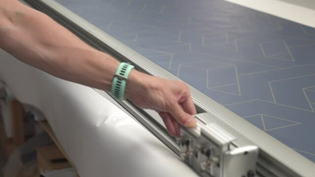 Graphic design cutting off excess vinyl material using industrial guillotine