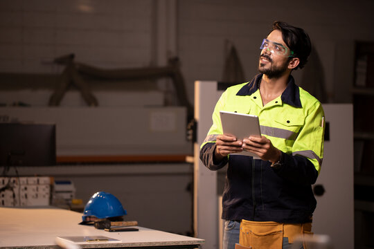 Handsome engineer man using tablet and fluorescent smart digital glasses with futuristic holographic interface to display data and repair defects of equipment in the wood factory. - Powered by Adobe