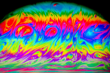 Closed up colourful wave and patterns with rainbow effects in bubbles isolated on black background.	