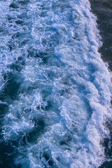 Water surface wave of rough deep turquoise and dark blue pacific sea with white foam texture background.	