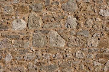 Background texture of newly repaired wall made with cream coloured stones and cement