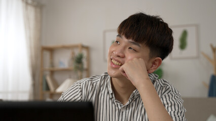 closeup of a daydreaming asian businessman looking away into empty space and propping face giggling...