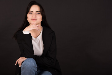 Portrait of an Armenian brunette girl in a black jacket on a black background.