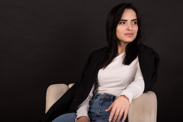 Portrait of an Armenian brunette girl in a black jacket on a black background.