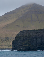 Impressive steep cliffs and rocky coastline silhouette coast of Faroe Islands in Atlantic Ocean on...