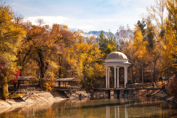 Fototapeta na wymiar White rotunda in beautiful autumn park amidagainst the background of mountains. 