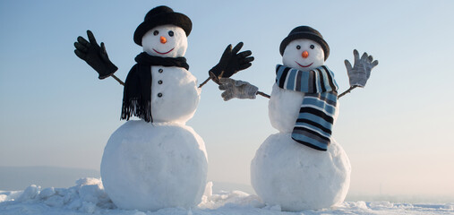 Snowmen holding hands outdoors. Winter snowman in black hat, scarf and gloves. Christmas winter banner with snowman. Winter greeting card with with snowman.