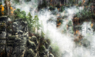 Misty weather in colorful autumn forest and rock formations