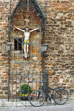 Old bicycle leaning against a statue of  statue of Jesus Christ at city Aachen, Germany