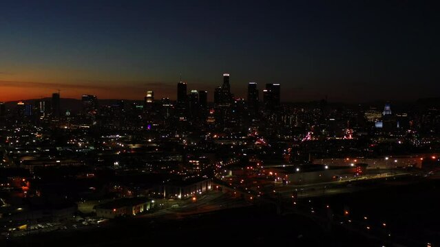 Night cityscape of Los Angeles showing illuminated buildings during golden hour. Aerial.