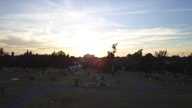 Aerial view of graveyard during golden hour, on outskirts of city. Silhouette.