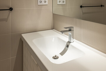 Brand new water tap in beige tiled luxury bathroom. Modern interior in detail.