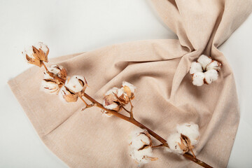 Beige napkin and cotton branch. The concept of natural ecological fabrics.