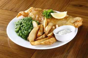 Fish and chips, with greens, potato wedges, lemon, and garlic dip