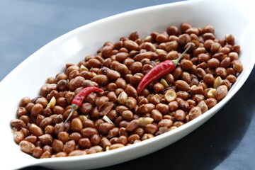 Roasted peanuts in a platter with chilli peppers and beer