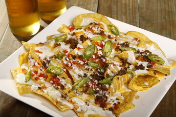 Nachos topped with cheese, garlic sauce, tomatoes and jalapenos