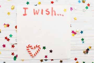 notebook with wish list on vintage wooden table with candy canes. christmas planning concept.