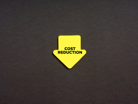 Cost reduction in business and finance concept. The word cost reduction on an arrow shaped note paper.