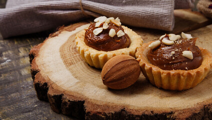 sweet chocolate muffins and cookies nut with condensed milk on a wooden stand with burlap on the table. still life