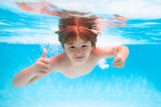 Child face underwater with thumbs up. Summer kids portrait in sea water on beach. Child swim and dive underwater in the swimming pool. Active healthy holiday.