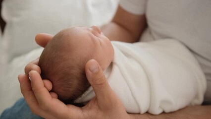 Adorable newborn baby sleeping on his father legs and dad rocking kid. Sweet infant child swaddled in blanket napping and his parent cares him