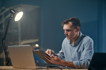 young businessman works with documents in a night office .